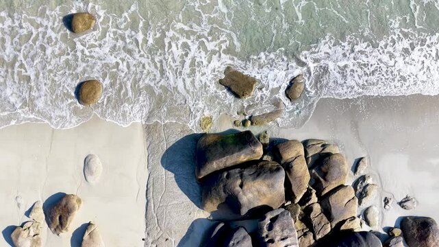 Spektakul&auml;re Drohnenaufnahme vom Plage de Boutrouilles: Wellen treffen auf feinen Sandstrand und imposante, runde Granitfelsen an der wilden K&uuml;ste der bretonischen Region.