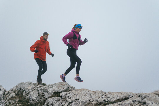 Trail running couple man and woman running on a mountain path