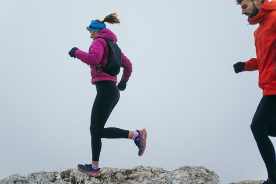 Trail running couple man and woman running on a mountain path