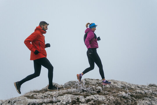 Trail running couple man and woman running on a mountain path