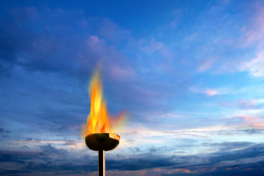 Close up burning flaming torch over blue sky