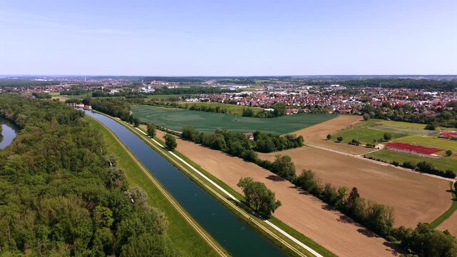 High angle drone shot of the artificial Illerkanal waterway near Illertissen town. Beautiful panoramic view of the agricultural fields, historic canal paths and rural green environment.