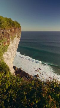 Dramatic Karang Boma Cliff Rising Above Powerful Ocean Waves Along Rugged Tropical Coastline During Golden Hour