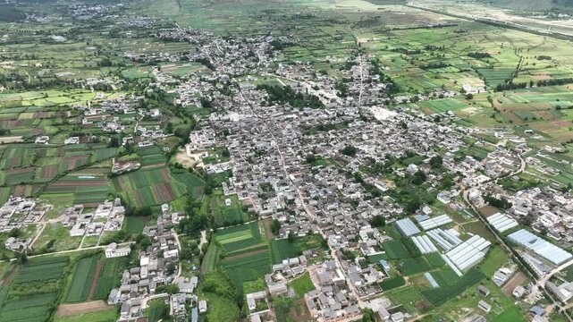 Aerial view of rural town surrounded by farmland and greenhouses