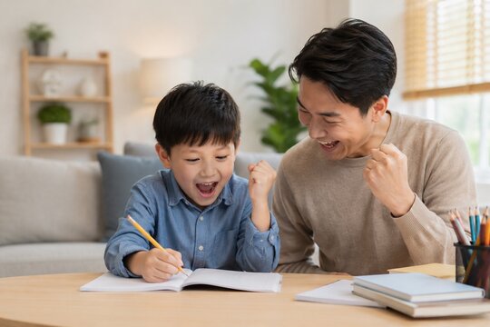 Happy Asian father encouraging and helping his young son with homework, elementary education and parenting concept