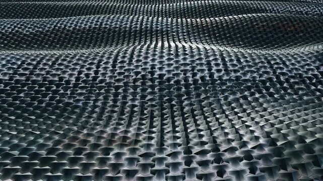 Seamless loop animation of abstract dark metallic geometric waves. Futuristic 3D rendering of an undulating kinetic surface texture, perfect for modern technology backgrounds, cyber concepts, and moti