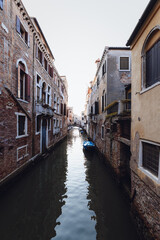 Obraz premium Narrow canal with a small blue boat, Venice, Italy