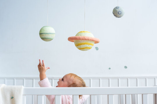 Baby reaching for planet mobile.