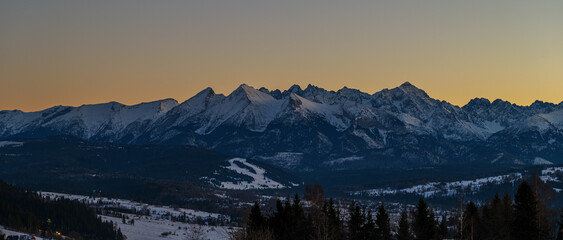 Majestic Tatra mountains landscape covered with snow in winter. Panoramic view of snowy rocky peaks against blue sky © FotoBastek