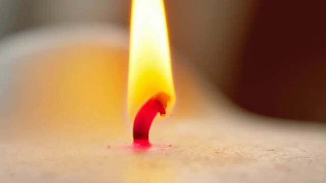 Burning candle wick melting into wax creating ambient light mood