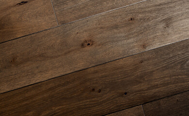 Obraz premium Dark brown rustic hardwood floor texture with knots and rough grain pattern, close-up diagonal view. Aged wooden planks with visible wear and natural imperfections, interior