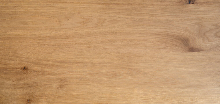 Natural light oak wood texture background with smooth flowing grain pattern. Single wide wooden plank surface close-up, clean minimal backdrop..