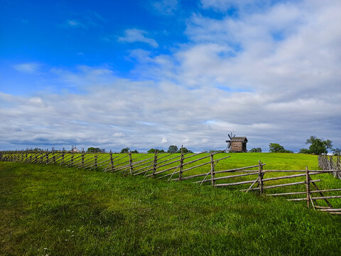 A windmill on a hill with a fence.