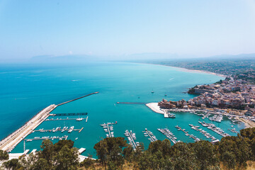 Obraz premium Aerial panoramic view of a picturesque Sicilian coastal town with a marina full of boats, turquoise sea and sandy beach stretching along the coastline in summer