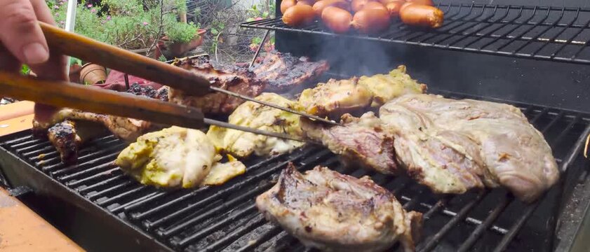 Hands Grilling Beef on a Barbecue &ndash; Close-Up of Meat Cooking on the Grill (asado)