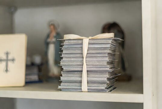a neat stack of small novena cards tied with a simple cotton ribbon, symbolizing repeated prayer, patience, and healing in silence