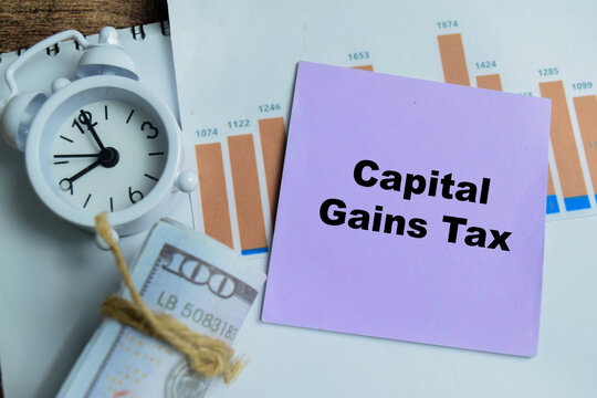 Concept of capital gains tax write on sticky notes isolated on Wooden Table. For sale of assets such as property, stocks or investments when their value has increased over time