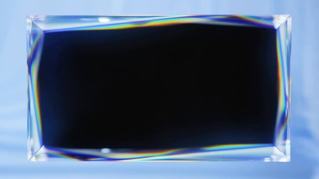Slow pan tracking shot of rectangular glass prism rotating and refracting rainbow light on blue studio background on tabletop glossy translucent crystal block subtle shift between frames