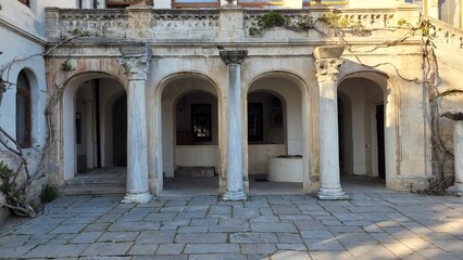 Obraz premium Ancient stone columns with richly decorated capitals in a historic stone-paved courtyard..