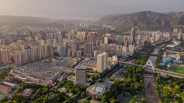 Aerial skyline of Lanzhou, China with river bridge and mountains at sunset