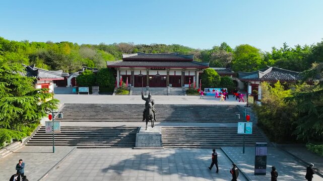 Traditional Chinese building with equestrian statue and stone steps in green park