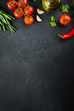 Fresh tomatoes, basil, rosemary, spices and pepper on black table. Flat lay image with space for design.
