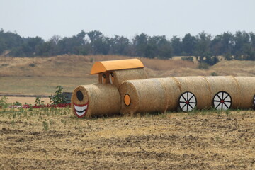 Obraz premium A dog-shaped installation made from straw bales in a field on a summer day