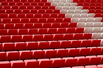 Fototapeta premium Empty red and white stadium seats in repeating rows create an abstract geometric pattern, evoking sports venues, empty grandstands, waiting spectators, and minimalist architecture