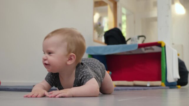 White infant trying to crawl on tile floor, focused look, soft lighting, soft play structure in the background, crawling forward, developing motor skills, cozy atmosphere of a room