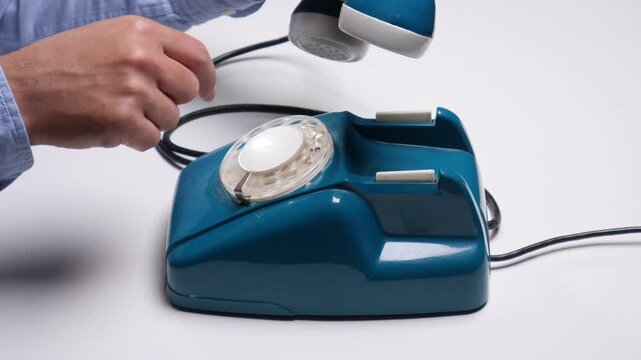 Man dialing numbers on an old blue rotary phone, connecting through classic analog telecommunications, representing historical technology, nostalgia, and vintage methods of calling