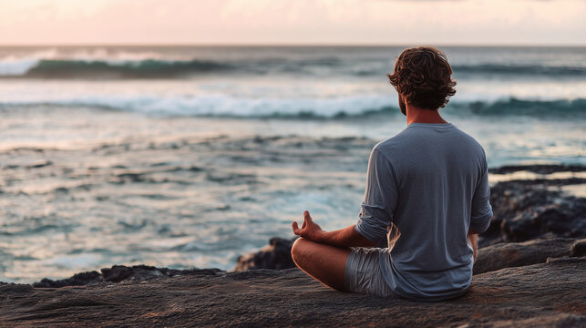 Man meditating on rocky beach by the sea at dusk, peaceful mindfulness practice near ocean waves, outdoor yoga retreat, mental clarity, stress relief, solitude, relaxation and emot