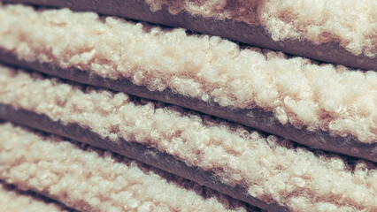 close up of stacked soft cream boucle blankets © irenka