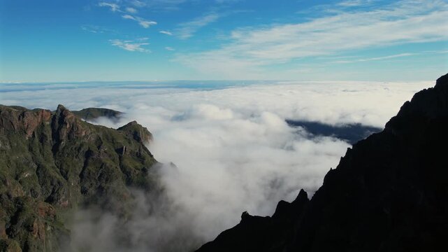 Stunning aerial footage revealing the magnificent mountain peaks of Pico do Arieiro in Madeira, Portugal, emerging from a sea of clouds