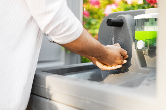 Man washing hands with soap and water at an outdoor portable sink. Proper hand hygiene and sanitation station for infection prevention at a campsite.
