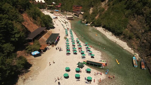 Breathtaking aerial drone view of Lake Komani in Albania. Vibrant turquoise water reservoir winding between mountains with a zigzag road in the foreground.