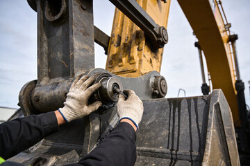 Mechanic wearing gloves carefully inspects and repairs heavy machinery joint © Snide12