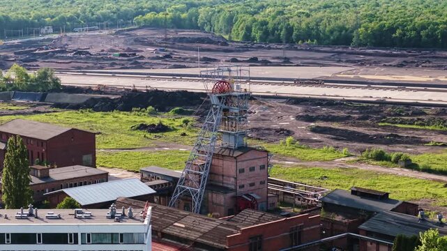 Aerial drone telephoto orbit shot of the historic Makoszowy coal mine complex in Zabrze, Poland. Zoomed-in rotation of the steel mine shaft tower.