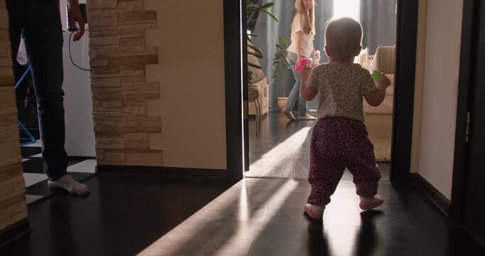 Toddler girl walking toward mother. Family support during first steps at home