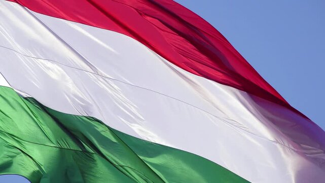 Hungarian flag, showcasing its horizontal tricolor design of red, white, and green. The flag is captured waving gently in the breeze against a clear sky
