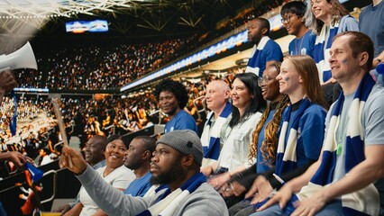 Excited football fan leader using bullhorn to unite blue supporter group in stadium stands during live soccer match atmosphere, Passionate football fans in the supporter section singing chants. © DC Studio