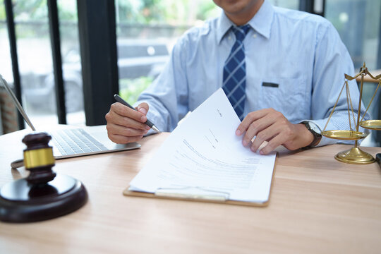 Businessman Reviewing Legal Documents with Laptop and Scales of Justice in Law Setting
