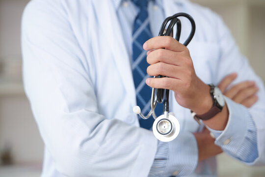 Professional doctor holding a stethoscope with arms crossed in a clinical setting