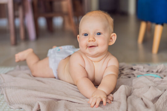 Baby lying on play mat learning to crawl and get on all fours. Infant practicing motor skills and development at home. Early childhood growth, milestones and active learning concept