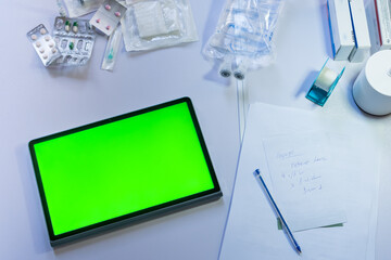 Fototapeta premium Medical supplies and digital tablet with green screen on a doctor's desk