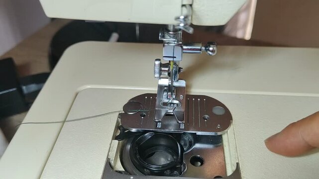Seamstress hands inserting bobbin into sewing machine