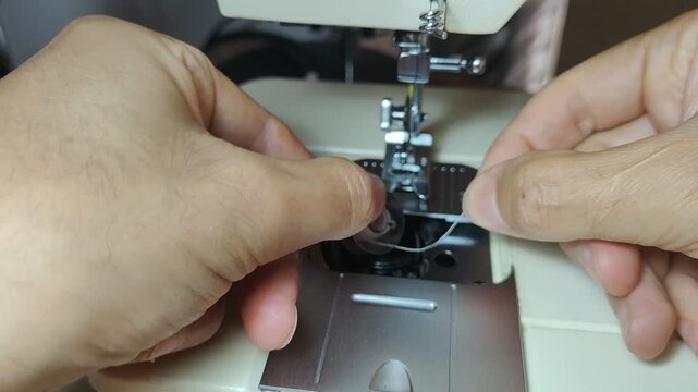 Seamstress inserting a threaded bobbin into a sewing machine