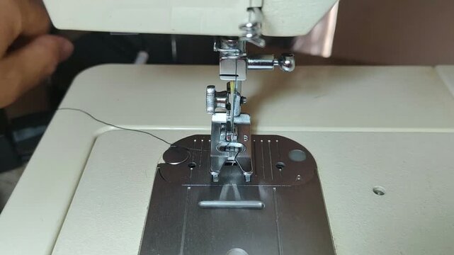 Person threading a sewing machine needle