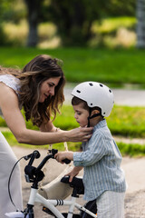Naklejka premium Mother helping son wearing safety helmet before bicycle ride