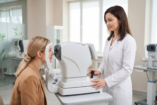 Female optometrist conducting eye examination with patient using autorefractor machine in clinic
