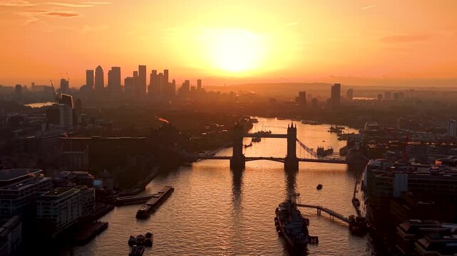 Aerial sunrise view of the cityscape of London, UK, with Tower Bridge, river Thames and the silhouette of Canary Wharf in the background